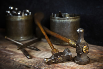 old vintage hammers and hallmark steel punches on a rustic wooden workbench of a goldsmith against...