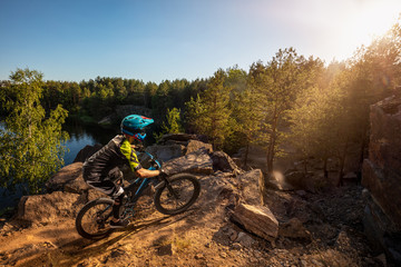 Mountain biker on forest trail near the lake. Male cyclist rides the rock