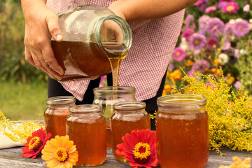 Woman holding bottle of honey. Autumn harvest.