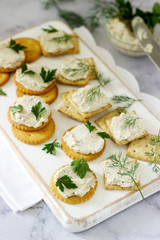 Snack from crackers and curd fish paste with herbs on a light background.