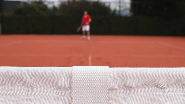 Abstract shot of a male playing tennis. Focus on the net. Player Out of foces. Timelapse