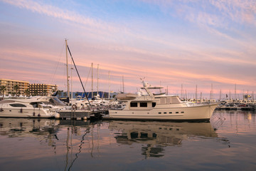 Fototapeta premium Beautiful port of Alicante, Spain at Mediterranean sea. Luxury yachts, ships, ferries and fishing boats sailing and standing in rows in harbor. Rich people traveling around the world. Sunset evening