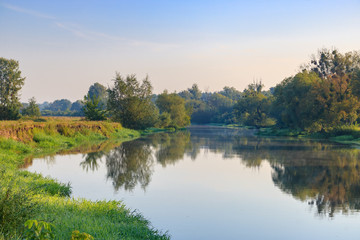 Fototapeta na wymiar River landscape on a background of blue sky at sunny summer morning