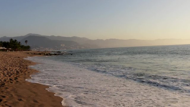 Waves from the Pacific Ocean crashing on the beach during a sunset in Puerto Vallarta, Jalisco, Mexico.