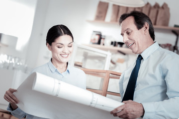 Obraz premium New scheme. Two professional architects standing with a big scheme and smiling while looking at it