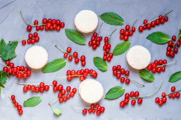 Food flatlay: macaroons, fresh red currant berries, green mint leaves lying on gray concrete background