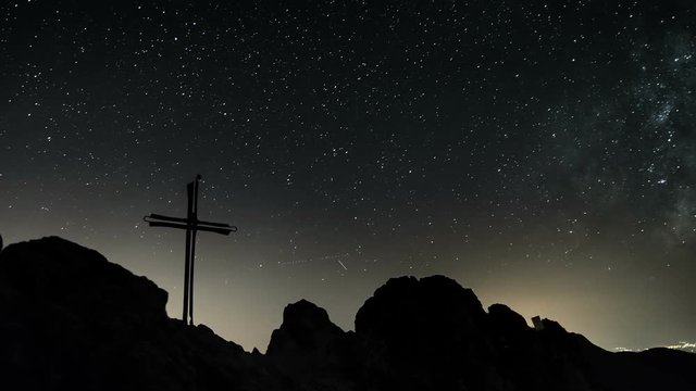 Stars with milky way galaxy moving over cross in top of the mountains Time lapse