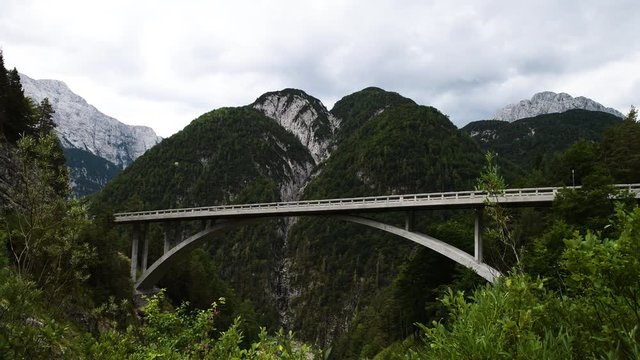 Arched bridge over a mountain river gorge in European Alps with mountain in background and cloudy skies. Mangart saddle pass in Julian alps, Slovenia