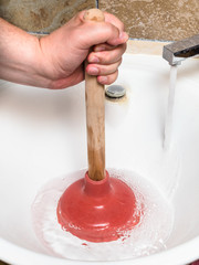 Fototapeta na wymiar plumber clears blockage in sink drain by plunger