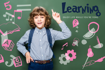 schoolboy showing idea gesture near blackboard, with icons and "learning - enjoy life while youre yong" lettering
