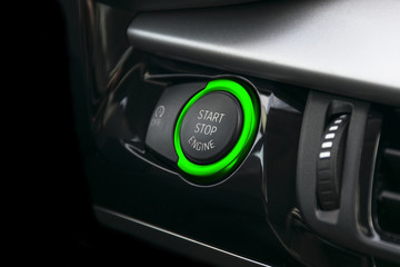 Car dashboard with focus on green engine start stop button. Car interior details. Car detailing