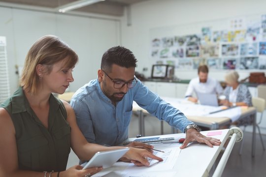 Executives discussing over blueprint on drafting table