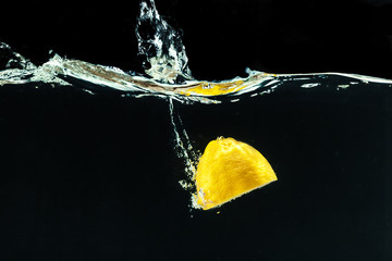 Fototapeta na wymiar fresh yellow lemon in water splash on black background