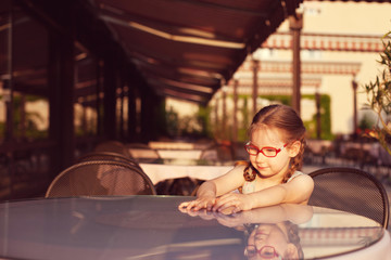 Fototapeta na wymiar young girl with glasses and dress is sitting at a table in a cafe