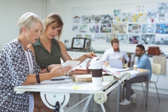 Female executives discussing over digital tablet on drafting