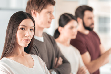 Fototapeta premium Team leadership. Smart Asian woman looking at you while standing together with her team