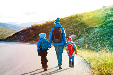 father with two kids walking on scenic road, family travel