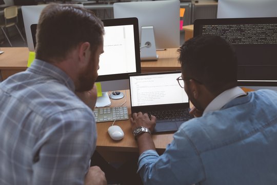 Executives discussing over laptop at desk in office