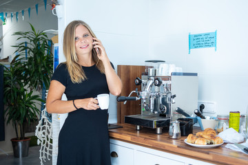 Young businesswoman having a coffee while attending her business by telephone