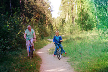 Obraz premium active senior grandmother with kids riding bikes in nature