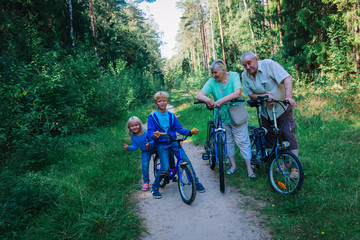 Naklejka premium active senior couple with kids riding bikes in nature