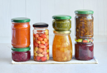 Fototapeta na wymiar Variety of preserved food in glass jars - pickles, jam, marmalade, sauces, ketchup. Preserving vegetables and fruits. Fermented food. Autumn canning. Conservation of harvest.