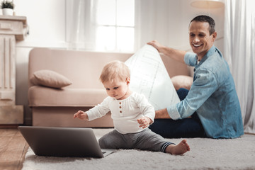 New generation. Smart cute baby looking at the laptop screen while sitting in front of the laptop