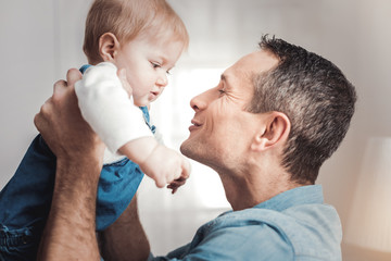 Fototapeta premium Newborn baby. Cute happy child looking at his father while being in his hands