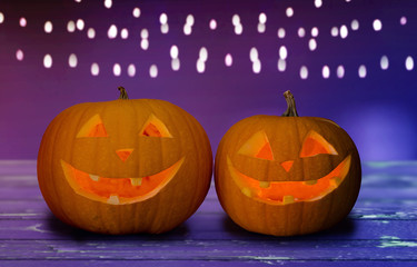 holidays, halloween and decoration concept - close up of carved pumpkins on table over ultra violet background