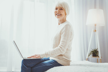 Be positive. Beautiful blonde woman sitting in semi position while posing on camera