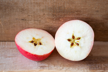 Cut apple on a wooden plank, showing the seeds in a delicate five pointed star motive