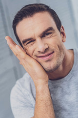 Obraz premium Touching face. Handsome hazel-eyed man touching his wrinkled face while feeling very thoughtful about upcoming situation