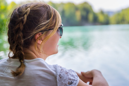 Junges M&auml;dchen sitzt am See und blickt in die Ferne