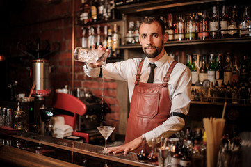 Bartender pourring a transparent cocktail into the cocktail glass