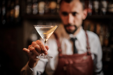Bartender holding a transparent cocktail in the martini glass