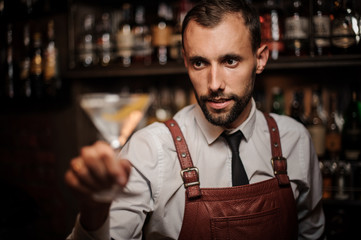 Smiling bartender holding a transparent cocktail in the martini glass