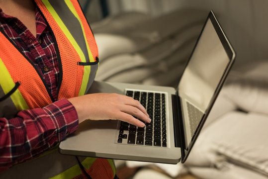 Female worker using laptop at  warehouse