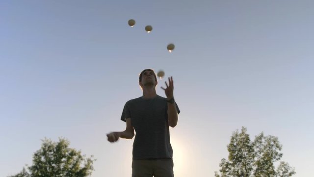 Man Concentrating Juggling Five Balls at Sunset
