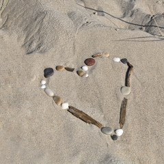 Fototapeta na wymiar Heart of sea shells and driftwood in the sand, perfect for tourism concept, love and leisure beach time