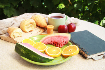 Morning flat lay with croissants,tea,fruits and notebook.