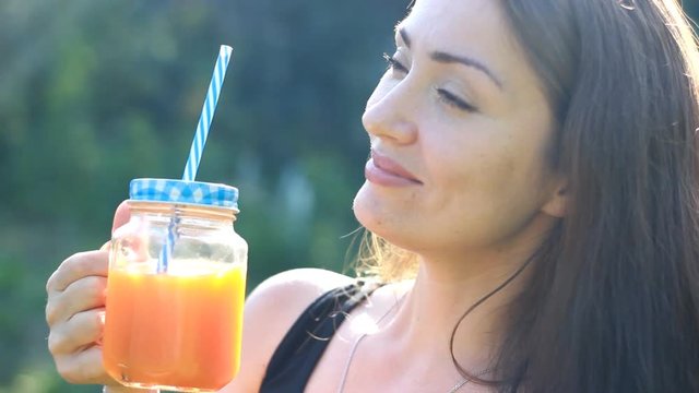 Woman drinks smoothies or orange fresh outdoors.