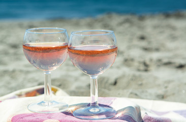 Beach party with sea view, romantic celebration on sunny sandy beach, two glasses with rose wine