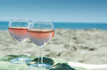Beach party with sea view, romantic celebration on sunny sandy beach, two glasses with rose wine