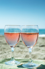 Beach party with sea view, romantic celebration on sunny sandy beach, two glasses with rose wine
