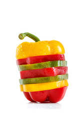 A selection of colorful sweet peppers sliced in pieces to make one pepper on white background