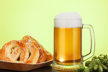 Pint of beer with ingredients for homemade beer on yellow with pretzel