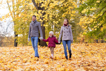 Obraz premium family, season and people concept - happy mother, father and little daughter walking at autumn park