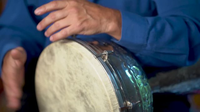 Closeup of playing fast drumming rhythm on metal Turkish daholla with arabic background.
