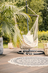 A cozy hammock with pillows on a deck in a green garden during summer vacation in a luxurious hotel.