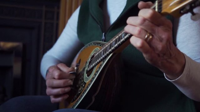 Full shot of woman playing folk tunes on the mandolin